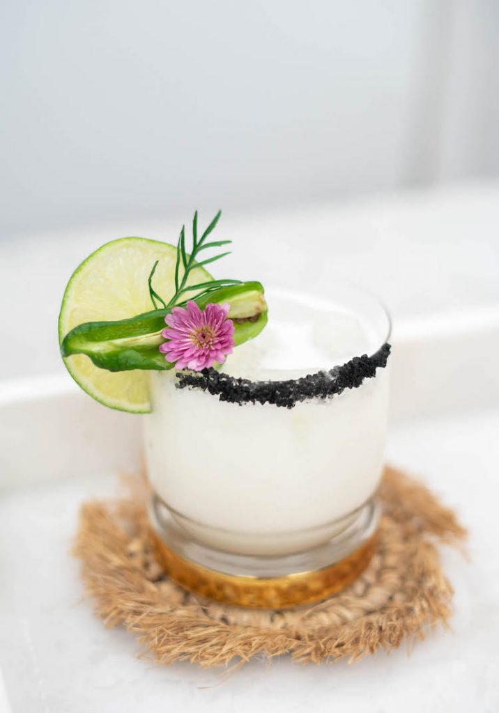 This Coconut Jalapeño Margarita is a spicy, tropical twist on the classic tequila cocktail. Black lava salt adds a striking rim to the white drink. Spicy jalapeño is tempered by cooling coconut for a refreshing, but zippy sip for Cinco De Mayo or any day of the year.