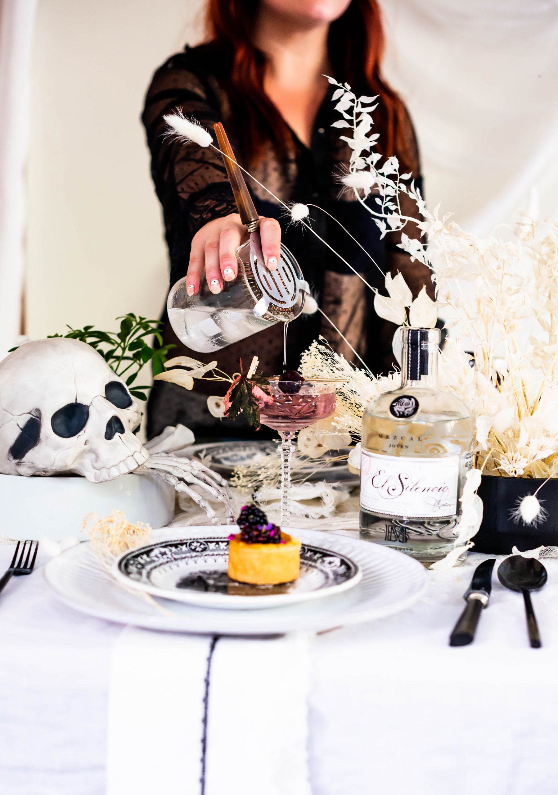 Pouring Mezcal martini Halloween cocktail on a spooky tablescape